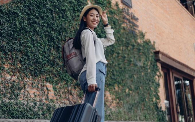 Felice viaggiatore femminile con zaino e bagagli