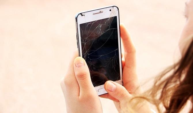 Una donna in possesso di uno smartphone rotto