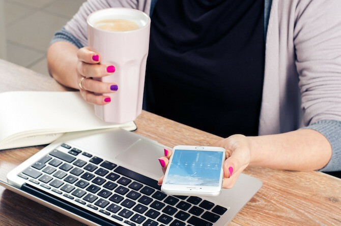 Donna che beve il caffè sul telefono e Mac