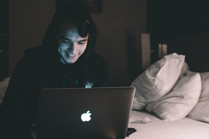 Persona che usa un laptop di notte seduta su un letto