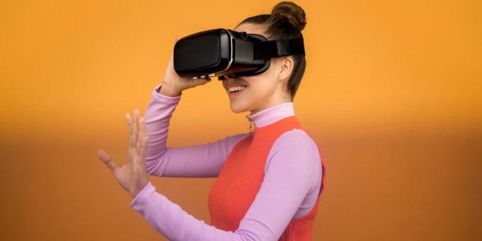 Donna sorridente mentre indossa un auricolare nero per realtà virtuale